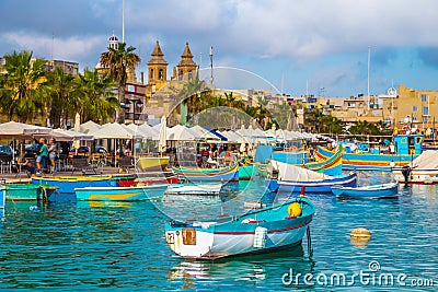 Marsaxlokk, Malta - Traditional colorful maltese Luzzu fisherboat at the old village of Marsaxlokk with turquoise sea water Editorial Stock Photo