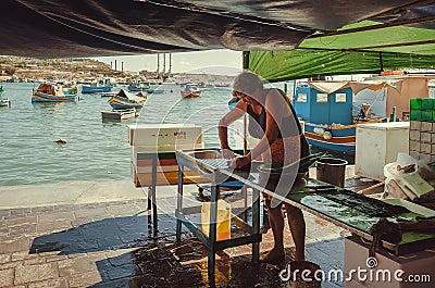 Woman cuts fish for customers on street bazaar of the fishing town Editorial Stock Photo