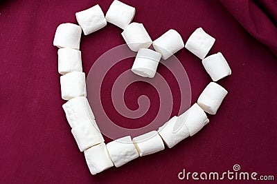 Marshmallows laid out in the shape of a heart isolated on a pink background. Bunch of small white marshmallows laid out in the for Stock Photo
