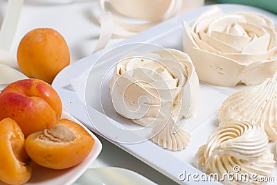 Marshmallows laid out on a tray. Nearby are ripe apricots Stock Photo