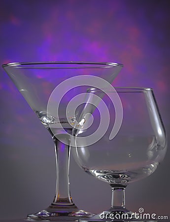 Martini Glass together with Cognac Glass with flashing bright violet lights on background Stock Photo