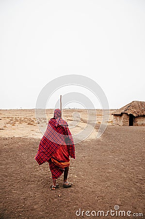 Masai or Maasai tribe man in red cloth in empty golden dusty land. Ngorongoro Consevation, Serengeti Savanna forest in Tanzania Editorial Stock Photo