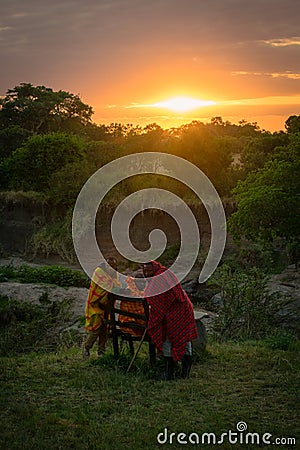 Masai Mara, Kenya, Africa â€“ August 10, 2018: A group of Masai men in traditional clothes resting at dawn after a long night Editorial Stock Photo