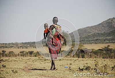 Masai Mara, Kenya - September 04, 2006: Masai tribal woman carrying her baby walking through the savanna Editorial Stock Photo