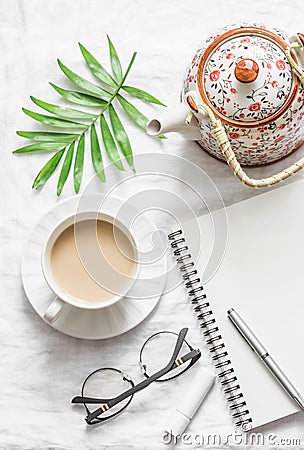 Masala tea, teapot, notepad, glasses, pen, green flower leaf on white background, top view. Morning inspiration planning. Stock Photo