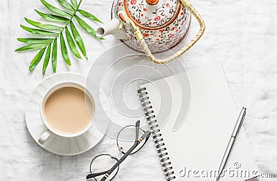 Masala tea, teapot, notepad, glasses, pen, green flower leaf on white background, top view. Morning inspiration planning. Stock Photo