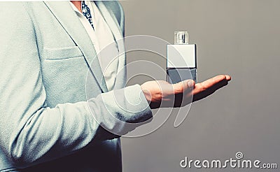 Masculine perfume, bearded man in a suit. Male holding up bottle of perfume. Perfume or cologne bottle and perfumery Stock Photo