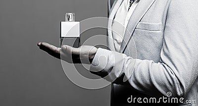 Masculine perfume, man in a suit. Man perfume, fragrance. Male holding up bottle of perfume. Perfume or cologne bottle Stock Photo