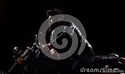 Masculinity concept. Macho, brutal biker in leather jacket riding motorcycle at night time, copy space. Man with beard Stock Photo