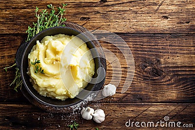 Mashed potatoes, boiled puree in cast iron pot on dark wooden rustic background, top view, copy space Stock Photo