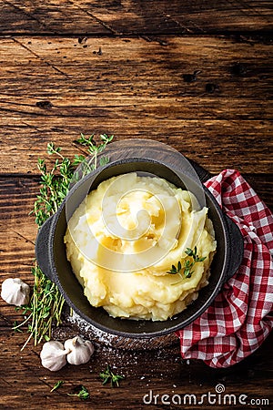 Mashed potatoes, boiled puree in cast iron pot on dark wooden rustic background, top view, copy space Stock Photo