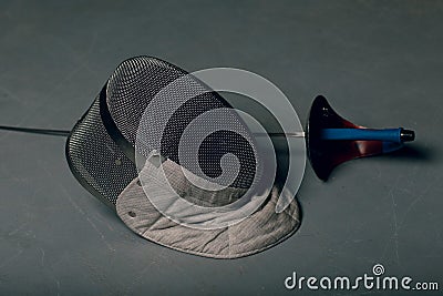 Mask and fencing epee on rgay background concept. Stock Photo
