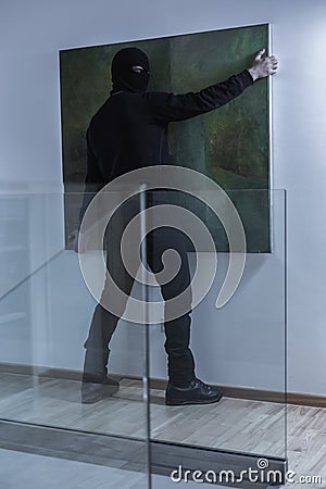 Masked burglar stealing valuable picture Stock Photo