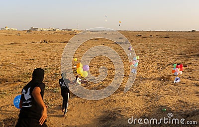 Masked Palestinians of the Popular Resistance Committees prepare incendiary balloons to be flown towards Israel Editorial Stock Photo
