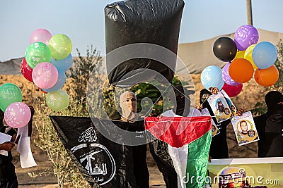 Masked Palestinians of the Popular Resistance Committees prepare incendiary balloons to be flown towards Israel Editorial Stock Photo