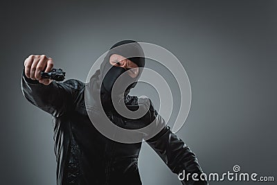 Masked robber with gun, looking into the camera. Stock Photo