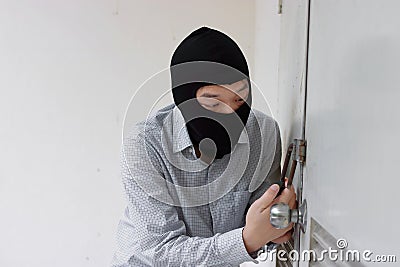 Masked robber using a lock picking tool to breaking and entering into a house. Criminal crime concept. Stock Photo