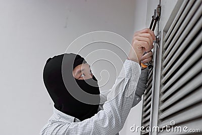 Masked robber using a lock picking tool to breaking and entering into a house. Criminal crime concept Stock Photo