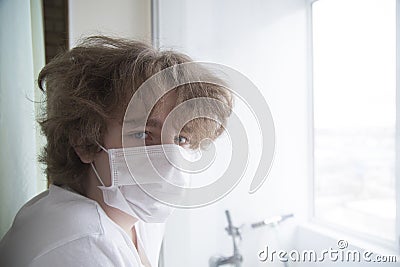 A masked teenager is being quarantined at home Stock Photo