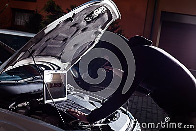 Masked thief hacker in a balaclava disarming car security systems Stock Photo