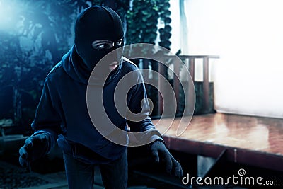Masked thief sneaking into house Stock Photo
