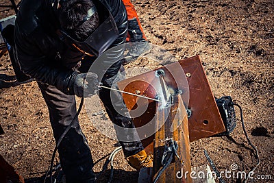 Masked welder welds metal at a construction site Stock Photo