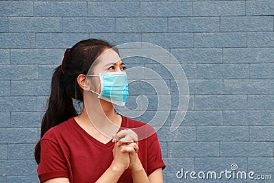 Masked woman keep the hands together to pray for good things to happen regarding epidemics and COVID Stock Photo