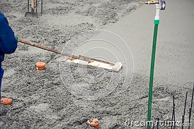 Mason building and leveling a first layer of fresh concrete floor at house foundation Stock Photo