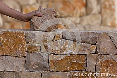 Mason hands working on masonry stone wall Stock Photo