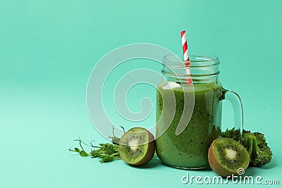 Mason jar with green smoothie and ingredients on mint background Stock Photo