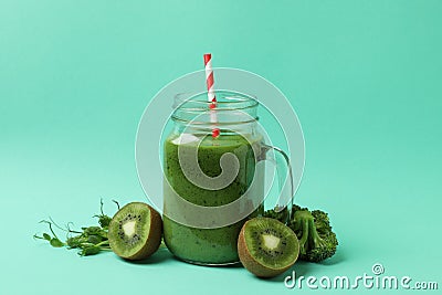 Mason jar with green smoothie and ingredients on mint background Stock Photo