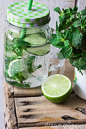 Mason jar mug with infused detox cucumber water with lime and mint, ingredients, spring, outdoors, cleansing Stock Photo