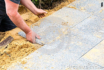 The mason lays gravel slabs on sand to make an alley Stock Photo