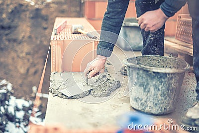 Mason working with construction spatula and leveling mortar for creating walls. Soft effect on photo Stock Photo