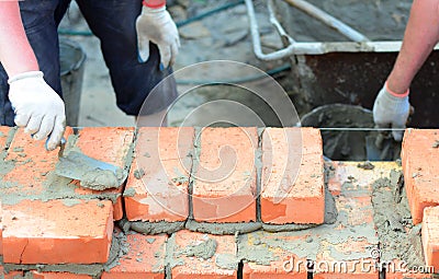 Masonry house wall construction.Bricklayers hands bricklaying house wall Stock Photo