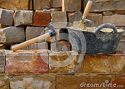 Masonry stone wall construction with tools Stock Photo