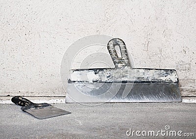 Masonry trowels near a grey plaster wall Stock Photo