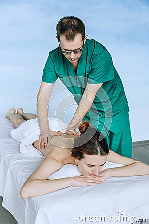 Massage therapist doing massotherapy of a young woman. Beautiful relaxed face of a young woman with brown hair and closed eyes Stock Photo