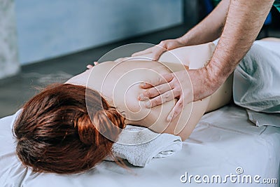 Massage therapist doing massotherapy of a young woman, elbow joint massage. Beautiful relaxed young woman Stock Photo