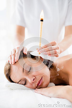 Masseur giving ear candle treament to woman Stock Photo