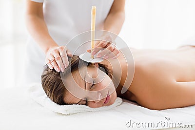Masseur giving ear candle treatmet to woman Stock Photo