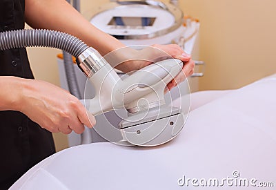 The masseur makes an hardware massage on the patient`s and legs in a white suit, close-up Stock Photo