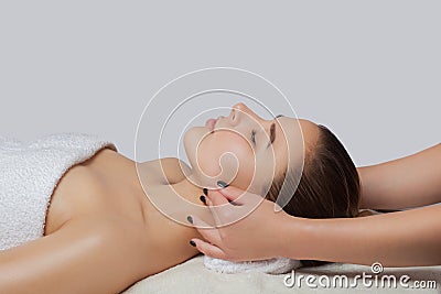 Masseur makes a relaxing massage on the ears, face, neck, shoulders and collarbones of a young beautiful woman in a spa. Stock Photo