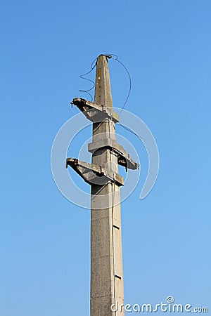 Massive concrete electrical utility pole with cut electrical wires hanging from top Stock Photo