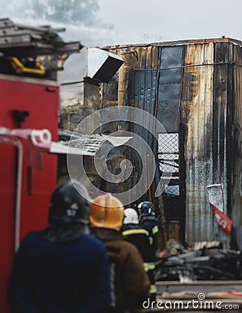 Massive large blaze fire in the city, blazing warehouse factory, storage building is burning, firefighters team putting out the Stock Photo