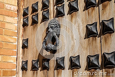 Massive wooden door with reinforced metal and old ornate lion door knocker Stock Photo