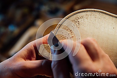 Master artisan luthier working on the creation of a violin. painstaking detailed work on wood. Stock Photo