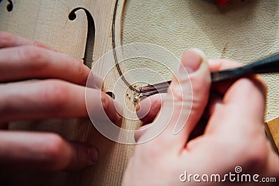 Master artisan luthier working on the creation of a violin. painstaking detailed work on wood. Stock Photo