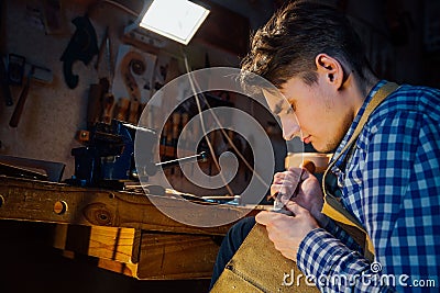 Master artisan luthier working on the creation of a violin. painstaking detailed work on wood. Stock Photo