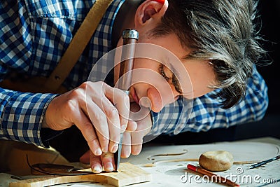 Master artisan luthier working on the creation of a violin. painstaking detailed work on wood. Stock Photo